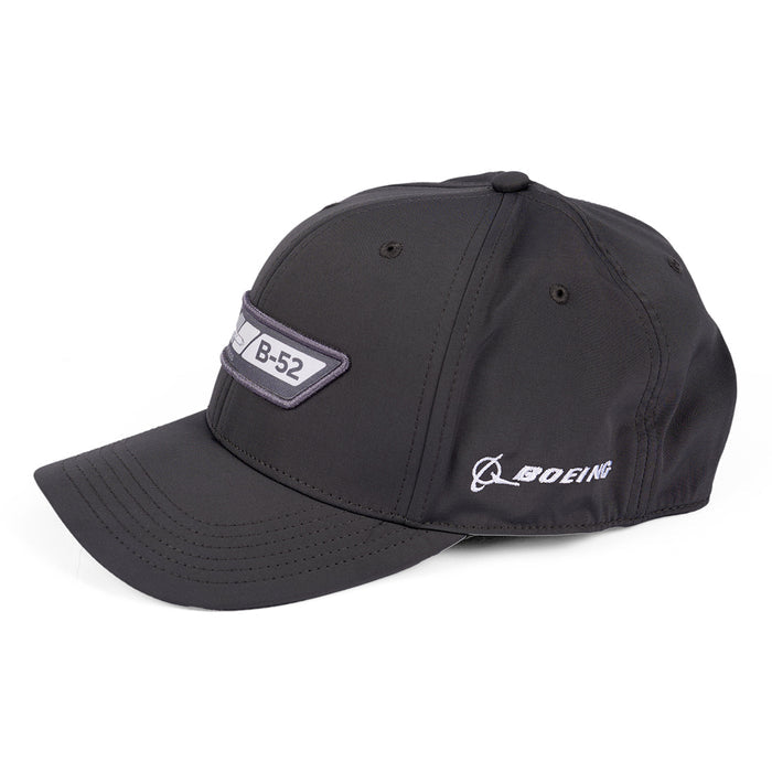 The Boeing B-52 Velocity Unisex Hat is a moisture-wicking black baseball cap featuring an embroidered B-52 patch on the front. The Boeing logo graces the side, and its displayed on a white background, combining style and functionality.